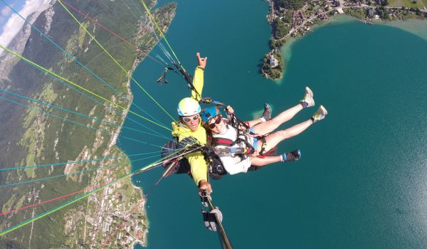 Deux personnes souriantes en plein vol en parapente, profitant de la vue et de la sensation de liberté dans les airs.