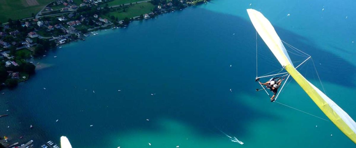 Un deltaplane décolle des hauteurs surplombant le lac d'Annecy.