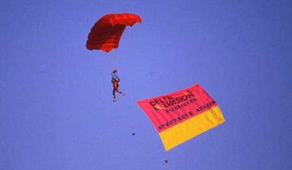 Photo vintage montrant les débuts du parapente avec un ancien modèle en vol