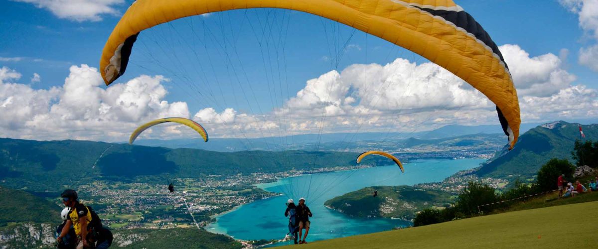 Décollage en parapente au-dessus du lac d'Annecy, offrant une vue spectaculaire sur les montagnes et les eaux cristallines.