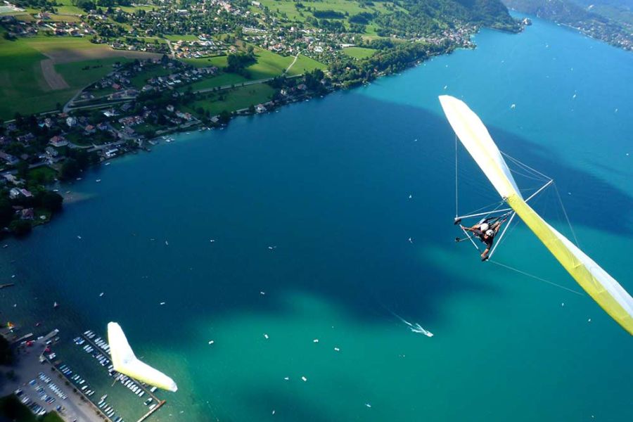 Un deltaplane décolle des hauteurs surplombant le lac d'Annecy.