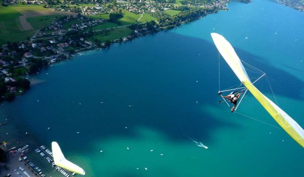 Un deltaplane décolle des hauteurs surplombant le lac d'Annecy.